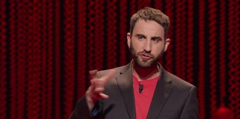 Movie still from “All About Gila” (2022), directed by Arturo González-Campos – A man in a red shirt and black jacket; Close Up shot, Over the shoulder angle