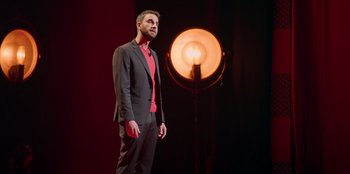 Movie still from “All About Gila” (2022), directed by Arturo González-Campos – A man standing in front of an orange light; Medium shot, Low angle