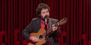 Movie still from “All About Gila” (2022), directed by Arturo González-Campos – A man with a beard is holding a guitar; Medium shot, Over the shoulder angle