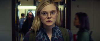 Movie still from “All the Bright Places” (2020), directed by Brett Haley – A woman with glasses is standing in front of a wall; Close Up shot, Over the shoulder angle