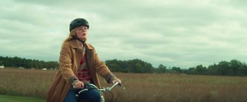 Movie still from “All the Bright Places” (2020), directed by Brett Haley – A woman riding a bicycle in a field; Medium shot, Low angle