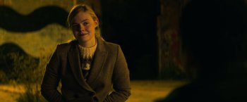 Movie still from “All the Bright Places” (2020), directed by Brett Haley – A woman in a suit and a sweater smiling for the camera; Medium shot, Over the shoulder angle