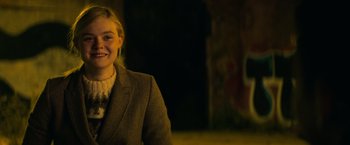 Movie still from “All the Bright Places” (2020), directed by Brett Haley – A woman in a suit smiling for the camera; Medium shot, Over the shoulder angle