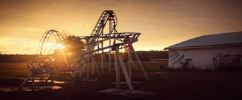 Movie still from “All the Bright Places” (2020), directed by Brett Haley – A view of a roller - coaster at sunset; Extreme Wide shot, High angle