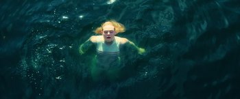 Movie still from “All the Bright Places” (2020), directed by Brett Haley – A woman swimming in a body of green water; Medium shot, Overhead angle