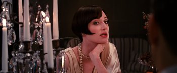 Movie still from “The Great Gatsby” (2013), directed by Baz Luhrmann – A woman sitting in front of a candle with pearls in her hair; Close Up shot, Over the shoulder angle