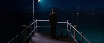 Movie still from “The Great Gatsby” (2013), directed by Baz Luhrmann – A man in a suit standing on a pier at night; Wide shot, High angle