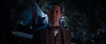 Movie still from “The Great Gatsby” (2013), directed by Baz Luhrmann – A man wearing a suit and bow tie in front of a house; Close Up shot, Low angle