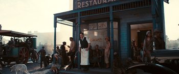 Movie still from “The Great Gatsby” (2013), directed by Baz Luhrmann – A group of people sitting outside of a restaurant; Wide shot, Low angle