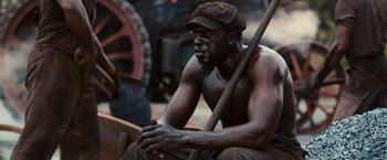 Movie still from “The Great Gatsby” (2013), directed by Baz Luhrmann – A man sitting on a bench holding a stick; Medium shot, High angle