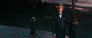 Movie still from “The Great Gatsby” (2013), directed by Baz Luhrmann – A man in a suit and hat standing next to a fire hydrant; Medium shot, Low angle