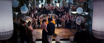Movie still from “The Great Gatsby” (2013), directed by Baz Luhrmann – Two people standing in front of a crowd at a party; Wide shot, High angle