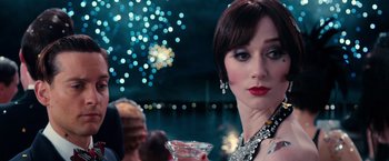 Movie still from “The Great Gatsby” (2013), directed by Baz Luhrmann – A woman in a black dress holding a glass of wine; Close Up shot, Over the shoulder angle