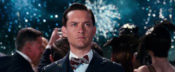 Movie still from “The Great Gatsby” (2013), directed by Baz Luhrmann – A person wearing a suit and bow tie; Close Up shot, Over the shoulder angle