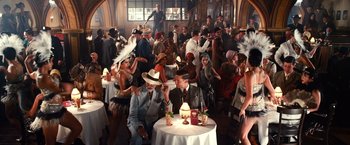 Movie still from “The Great Gatsby” (2013), directed by Baz Luhrmann – A group of people sitting at a table with drinks; Wide shot, High angle