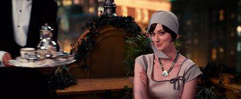 Movie still from “The Great Gatsby” (2013), directed by Baz Luhrmann – A woman wearing a headscarf sitting in front of a wooden bench; Close Up shot, Over the shoulder angle