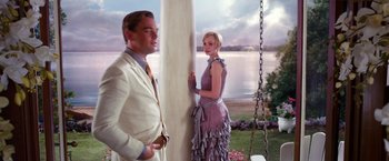 Movie still from “The Great Gatsby” (2013), directed by Baz Luhrmann – A man and a woman standing next to each other near a swing; Medium shot, Low angle