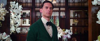 Movie still from “The Great Gatsby” (2013), directed by Baz Luhrmann – A man wearing a green sweater and a bow tie; Close Up shot, Low angle