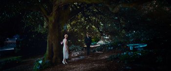 Movie still from “The Great Gatsby” (2013), directed by Baz Luhrmann – A man and a woman standing under a large tree; Wide shot, High angle