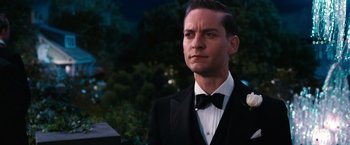 Movie still from “The Great Gatsby” (2013), directed by Baz Luhrmann – A man in a suit and bow - tie looking to his left; Close Up shot, Over the shoulder angle