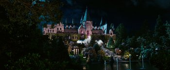 Movie still from “The Great Gatsby” (2013), directed by Baz Luhrmann – A large castle like building with a fountain in front of it at night time; Extreme Wide shot, High angle