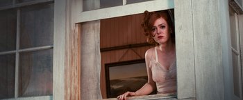 Movie still from “The Great Gatsby” (2013), directed by Baz Luhrmann – A beautiful young woman standing in front of an open window; Medium shot, Low angle