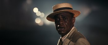 Movie still from “The Great Gatsby” (2013), directed by Baz Luhrmann – A man wearing a straw hat and a suit; Close Up shot, Over the shoulder angle