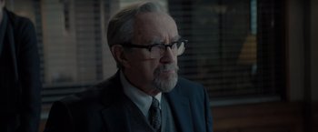 Movie still from “All the Old Knives” (2022), directed by Janus Metz – An older man wearing glasses and a suit; Close Up shot, Over the shoulder angle