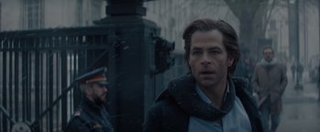 Movie still from “All the Old Knives” (2022), directed by Janus Metz – A man standing next to a building in the snow; Close Up shot, Over the shoulder angle