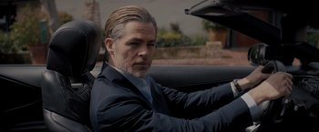 Movie still from “All the Old Knives” (2022), directed by Janus Metz – A person in a car wearing a suit; Close Up shot, Low angle