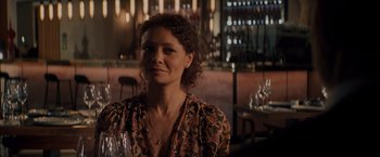 Movie still from “All the Old Knives” (2022), directed by Janus Metz – A woman sitting at a table in front of wine glasses; Close Up shot, Over the shoulder angle