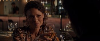 Movie still from “All the Old Knives” (2022), directed by Janus Metz – A woman sitting at a table holding a glass of wine; Close Up shot, Over the shoulder angle