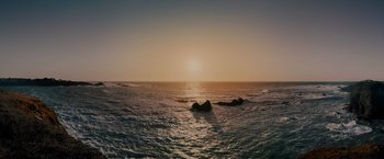 Movie still from “All the Old Knives” (2022), directed by Janus Metz – A body of water that has some rocks in the water; Extreme Wide shot, High angle