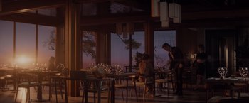 Movie still from “All the Old Knives” (2022), directed by Janus Metz – People are sitting at tables in a restaurant at night; Wide shot, Low angle