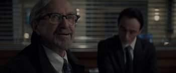 Movie still from “All the Old Knives” (2022), directed by Janus Metz – A man with a beard wearing glasses and a suit and tie; Close Up shot, Over the shoulder angle