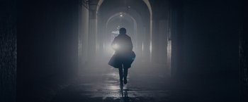 Movie still from “All the Old Knives” (2022), directed by Janus Metz – A person is walking in the dark with a bag; Wide shot, Low angle