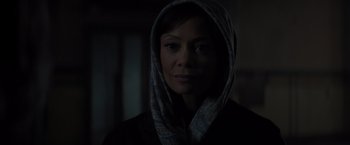 Movie still from “All the Old Knives” (2022), directed by Janus Metz – A woman wearing a head scarf in a dark room; Close Up shot, Low angle