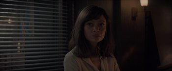 Movie still from “All the Old Knives” (2022), directed by Janus Metz – A woman in a white shirt is in a dark room; Close Up shot, Over the shoulder angle