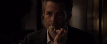 Movie still from “All the Old Knives” (2022), directed by Janus Metz – A person holding a piece of food; Close Up shot, Over the shoulder angle