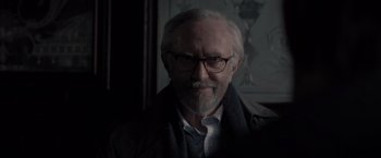 Movie still from “All the Old Knives” (2022), directed by Janus Metz – An older man with a beard and glasses; Close Up shot, Over the shoulder angle