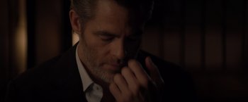 Movie still from “All the Old Knives” (2022), directed by Janus Metz – A person wearing a suit and holding his hand to his face; Close Up shot, Over the shoulder angle