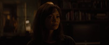 Movie still from “All the Old Knives” (2022), directed by Janus Metz – A woman with long brown hair is in a dark room; Close Up shot, Over the shoulder angle