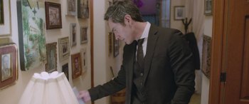 Movie still from “All the Places” (2023), directed by Pitipol Ybarra – A man in a suit and tie looking at a piece of paper; Medium shot, Over the shoulder angle