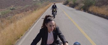 Movie still from “All the Places” (2023), directed by Pitipol Ybarra – Two people riding motorcycles down a road; Wide shot, High angle
