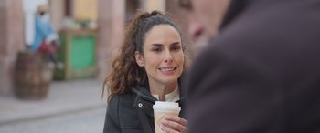 Movie still from “All the Places” (2023), directed by Pitipol Ybarra – A woman holding a cup of coffee on the sidewalk; Close Up shot, Over the shoulder angle