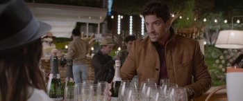 Movie still from “All the Places” (2023), directed by Pitipol Ybarra – A man sitting in front of a bunch of wine glasses; Medium shot, Over the shoulder angle