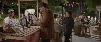 Movie still from “All the Places” (2023), directed by Pitipol Ybarra – A man and a woman standing in front of a bar; Medium shot, Over the shoulder angle