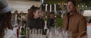 Movie still from “All the Places” (2023), directed by Pitipol Ybarra – A group of people sitting around a table with wine glasses; Medium shot, Over the shoulder angle