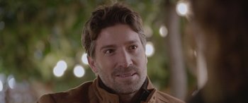 Movie still from “All the Places” (2023), directed by Pitipol Ybarra – A person wearing a brown jacket; Close Up shot, Over the shoulder angle