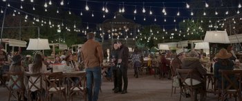 Movie still from “All the Places” (2023), directed by Pitipol Ybarra – Two people standing in front of each other at an outdoor restaurant; Wide shot, Over the shoulder angle